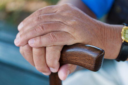 Hand eines ?lteren Mannes mit Gehstock. Senior mit Behinderung